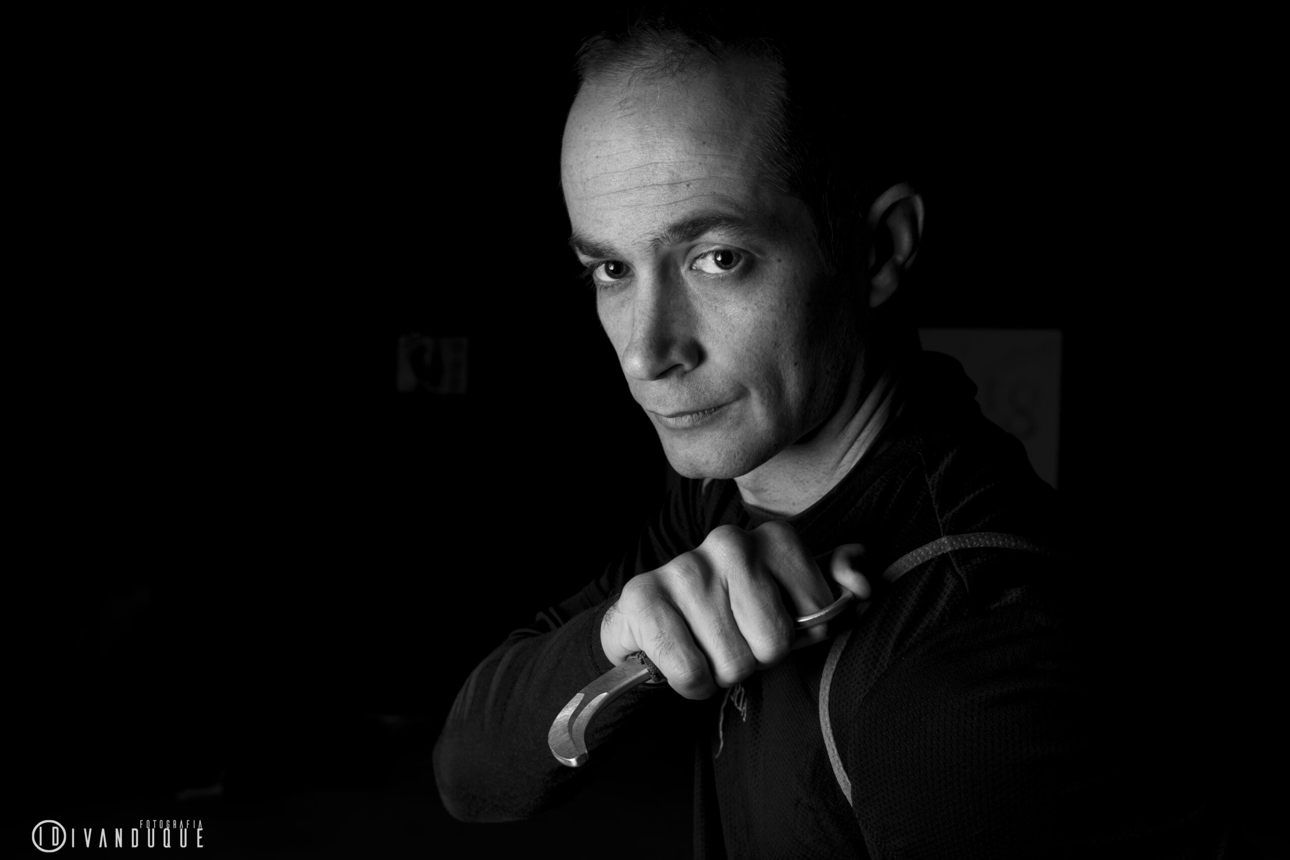 Sebastián Deibe en retrato en blanco y negro sosteniendo un karambit