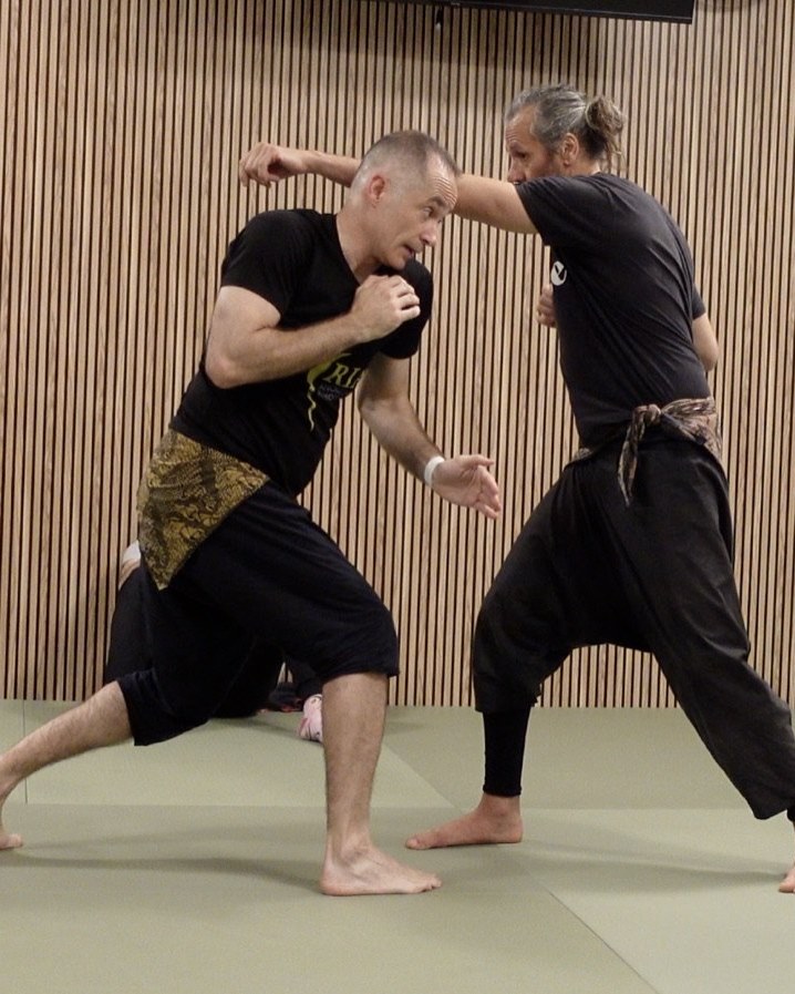 Dos practicantes de Satria trabajando una técnica de pie sobre el tatami