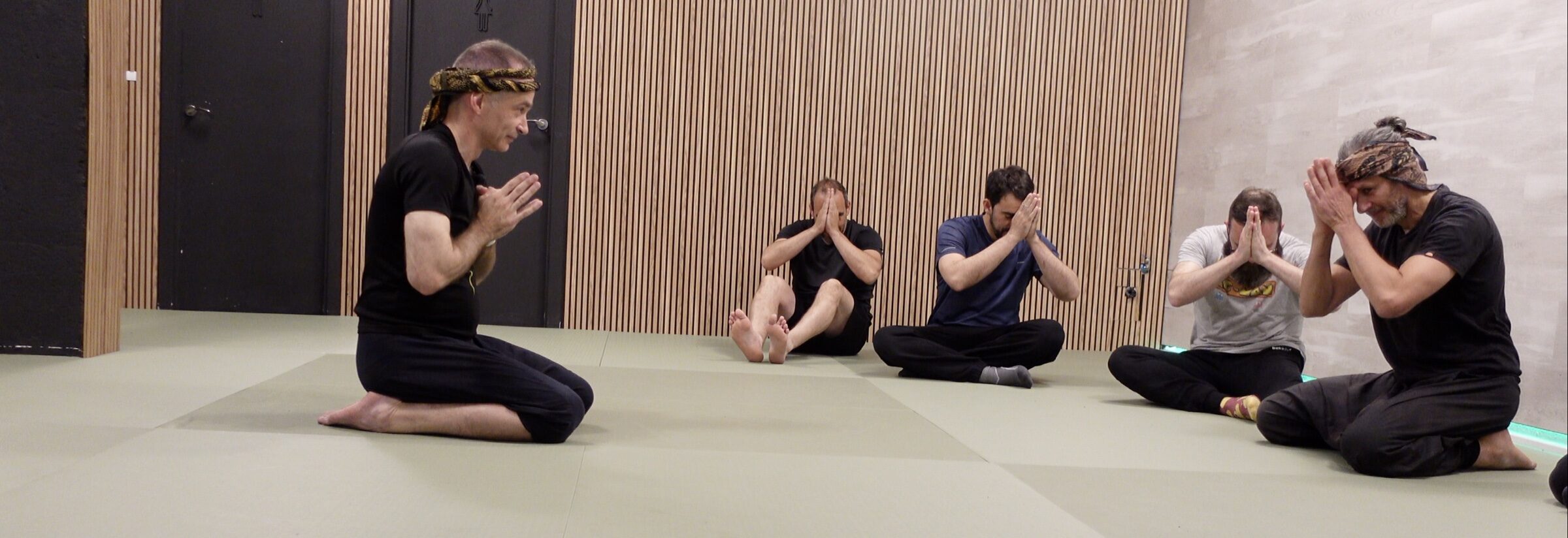 Grupo de alumnos y Sebastián Deibe de rodillas realizando el saludo sembah en el tatami