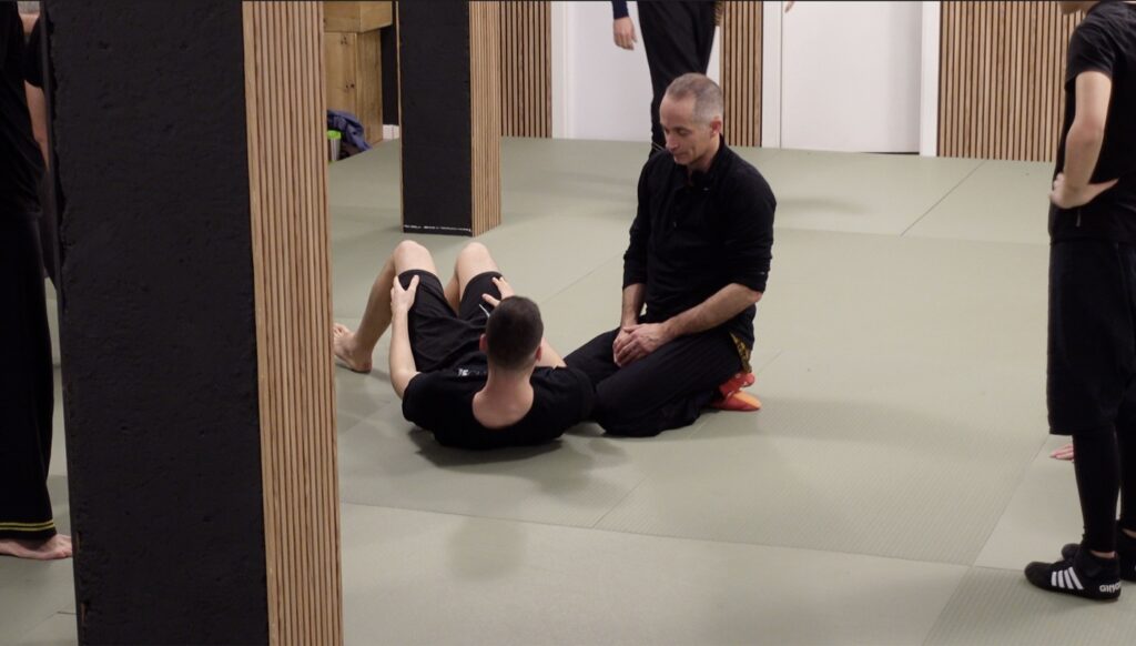 Sebastián Deibe acompañando a un alumno tumbado en el tatami