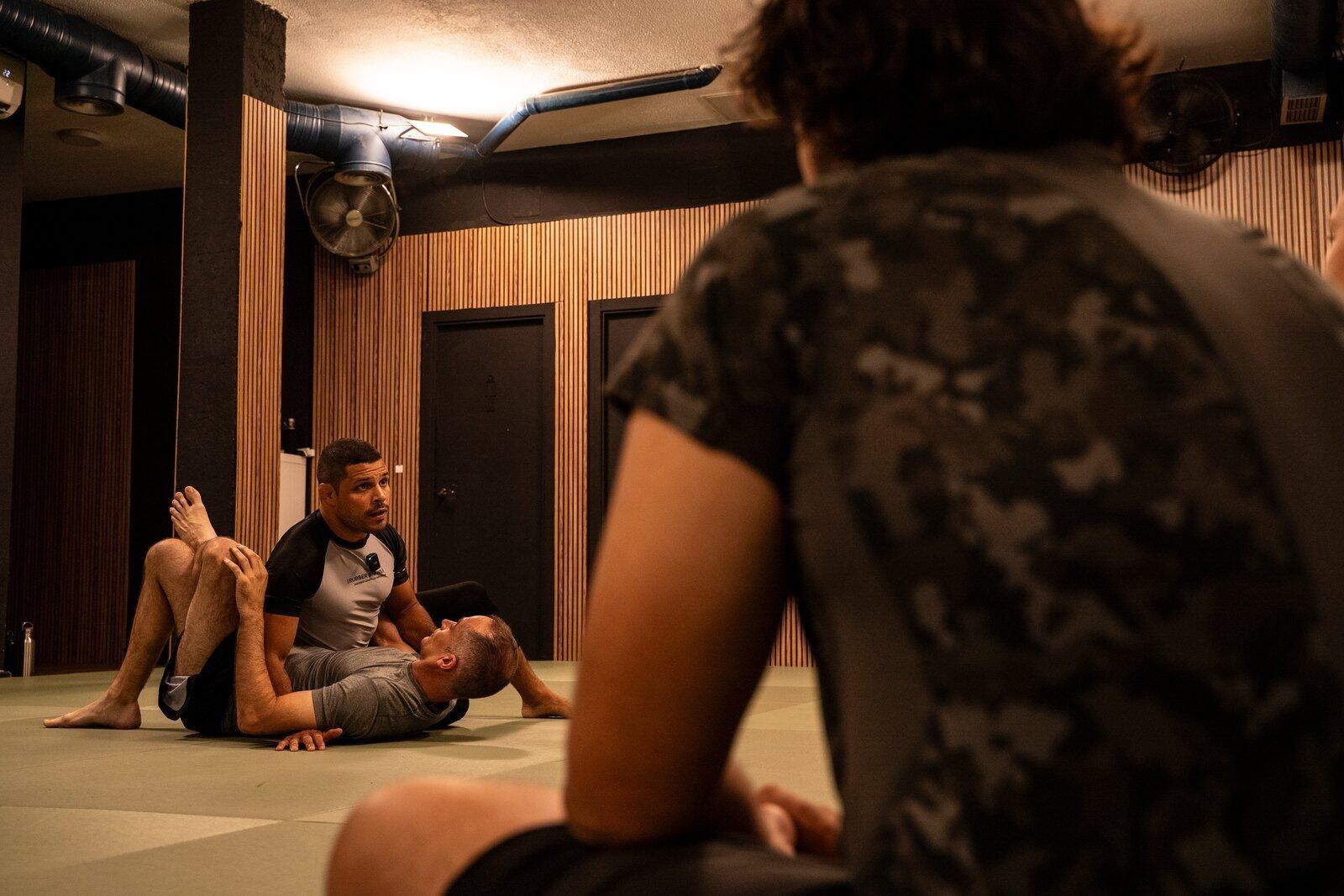 Clase de jiu-jitsu no-gi en DEIBE: alumnos observando un combate de suelo